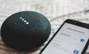 Turned-on charcoal Google Home Mini and smartphone photo